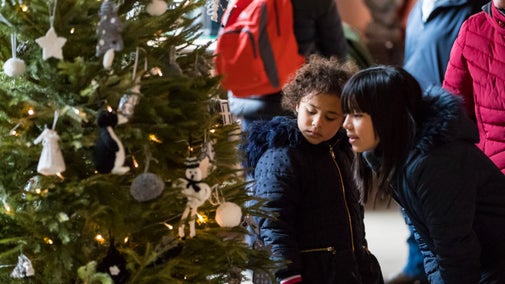 Child and women looking a Christmas tree covered in lights and festive decoration at Sudbury Hall and the Museum of Childhood, Derbyshire